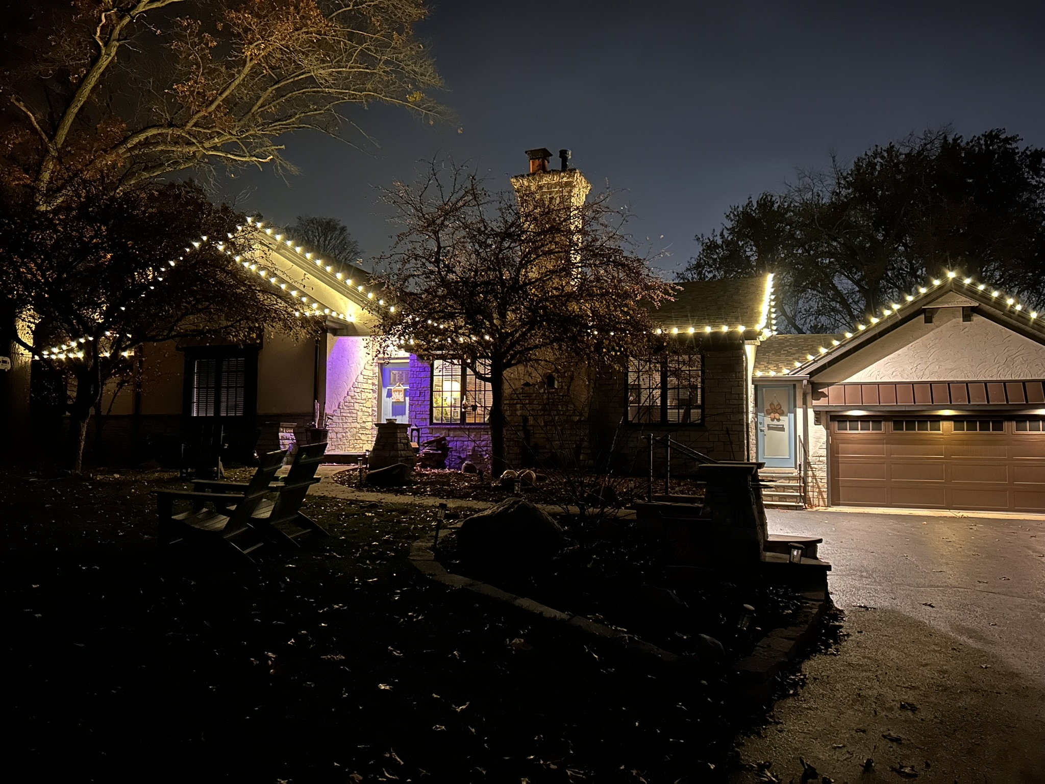 Home with warm white roofline lighting and a purple lit entryway